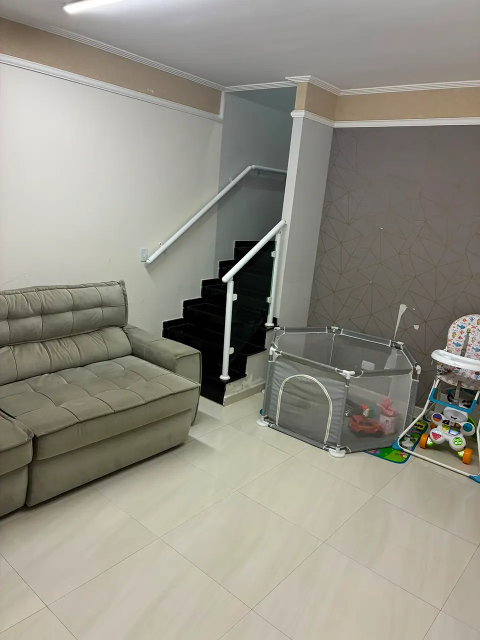 Sala com sofá e escada com guarda-corpo de vidro
